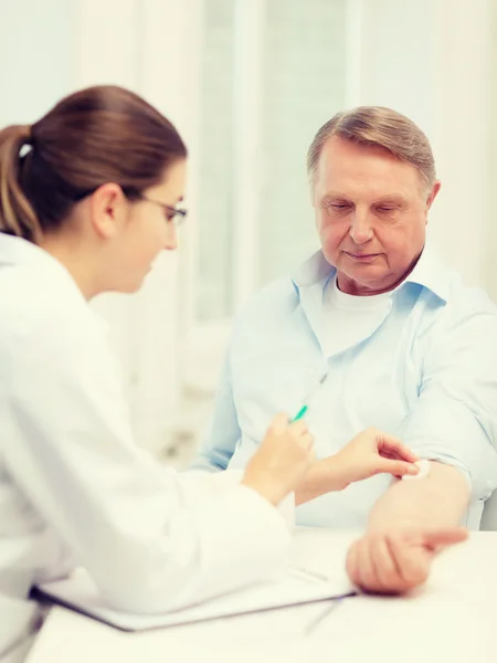 Female doctor doing injection to old man — Stock Photo, Image