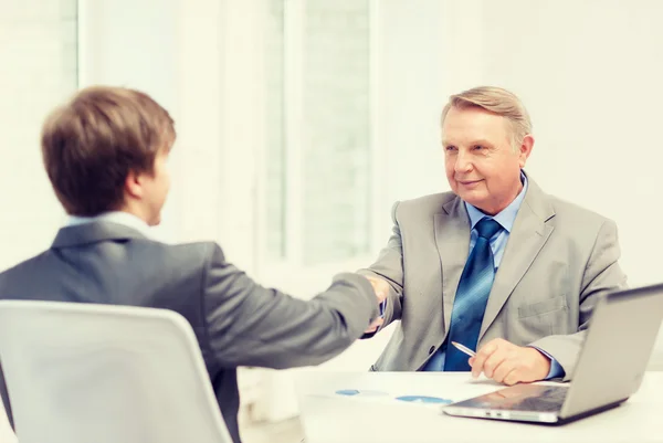 Older man and young man shaking hands in office — Stock Photo, Image