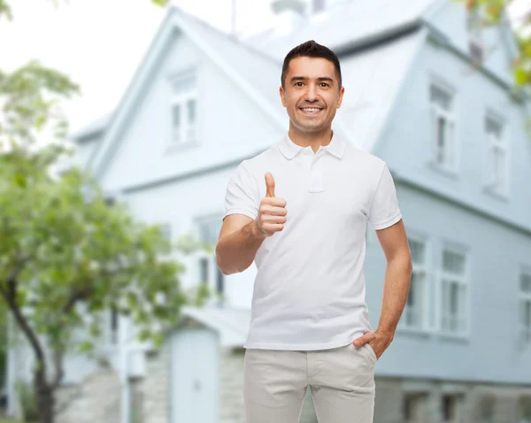 Uomo mostrando pollici sopra lo sfondo della casa — Foto Stock