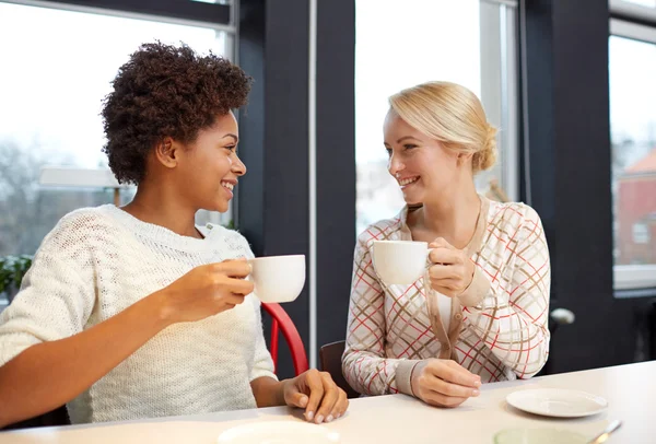 Happy young women drinking tea or coffee at cafe — Stock Photo, Image