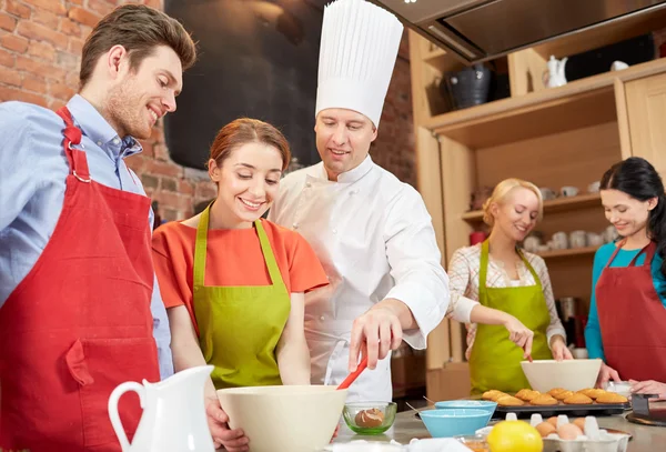 Amici felici e cuoco cuoco cottura in cucina — Foto Stock