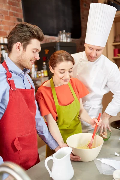 Happy couple and male chef cook cooking in kitchen — Stock Photo, Image