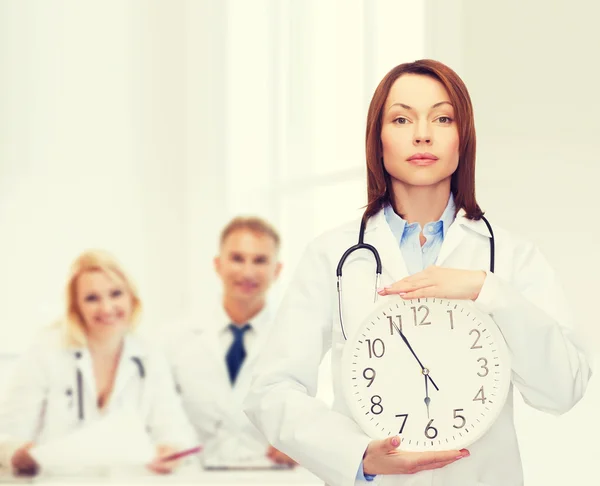 Calm female doctor with wall clock — Stock Photo, Image