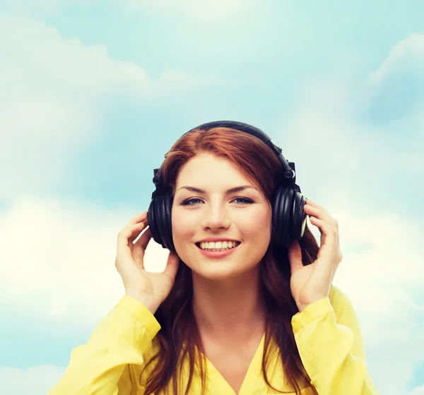 Sonriente chica joven en los auriculares en casa — Foto de Stock