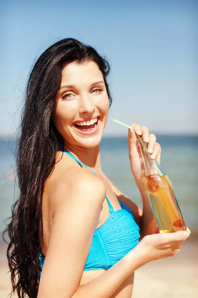 Flicka med flaska drink på stranden — Stockfoto