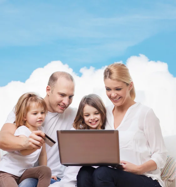 Happy family with laptop computer and credit card — Stock Photo, Image