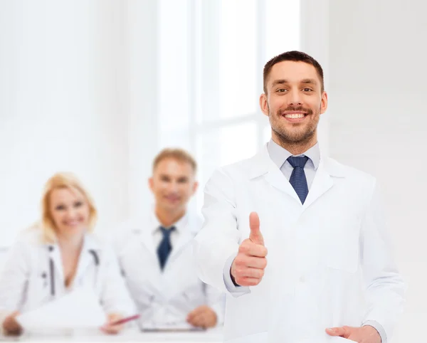 Usmívající se muž doktor ukazuje palec — Stock fotografie