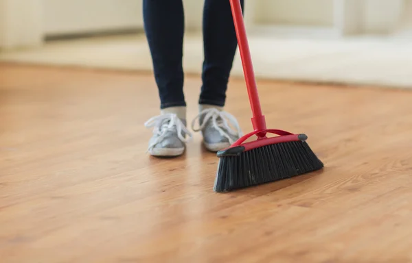 Close up of woman legs with broom sweeping floor — Stock Photo, Image