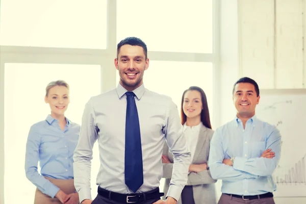 Lächelnder Geschäftsmann im Amt mit Team auf dem Rücken — Stockfoto