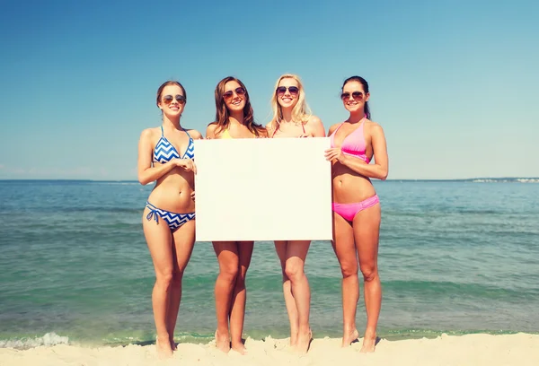 Grupo de mujeres sonrientes con tablero en blanco en la playa — Foto de Stock