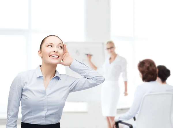 Lächelnde Geschäftsfrau hört verschmitzt zu Stockbild