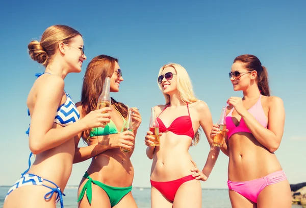 Group of smiling young women drinking on beach — Stock Photo, Image