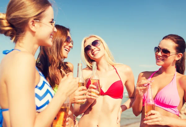 Grupo de mujeres jóvenes sonrientes bebiendo en la playa — Foto de Stock