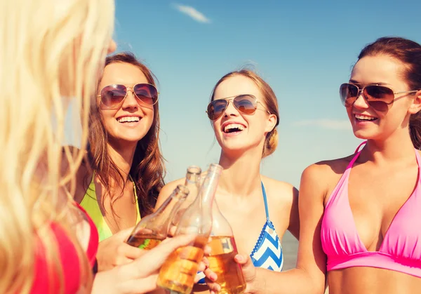 Group of smiling young women drinking on beach — Stock Photo, Image