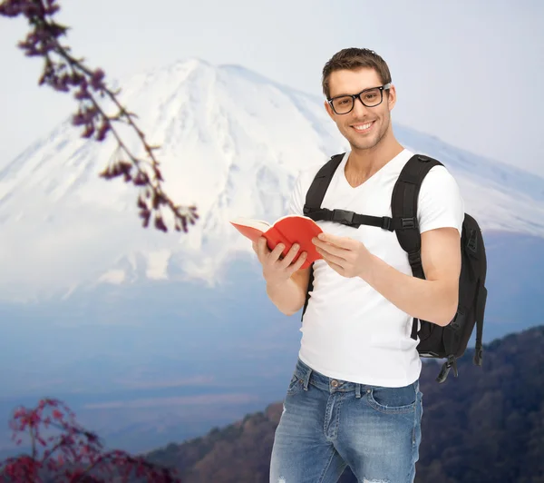 Joven feliz con mochila y reserva los viajes — Foto de Stock