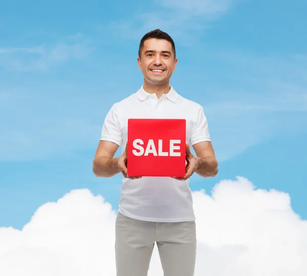 Smiling man with red sale sigh over blue sky — Stock Photo, Image