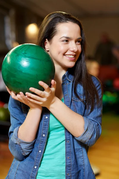Feliz jovem mulher segurando bola no bowling clube — Fotografia de Stock
