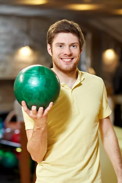 Happy young man holding ball in bowling club — Stock Photo, Image