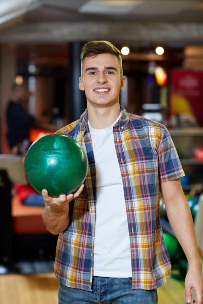 Heureux jeune homme tenant la balle dans le club de bowling — Photo