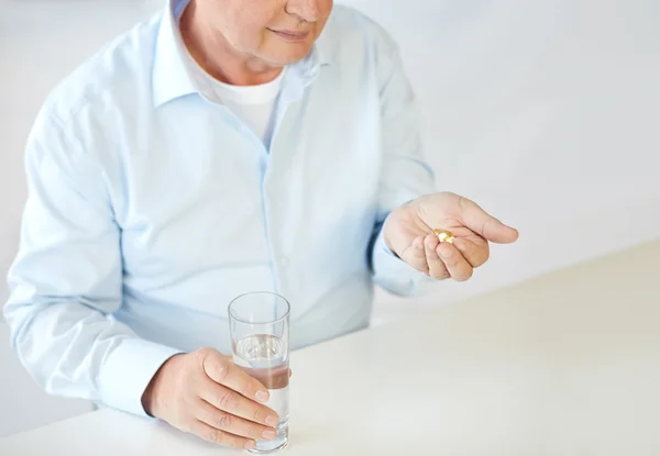 Κοντινό πλάνο της παλιάς άνθρωπος με χάπια και ποτήρι νερό — Φωτογραφία Αρχείου