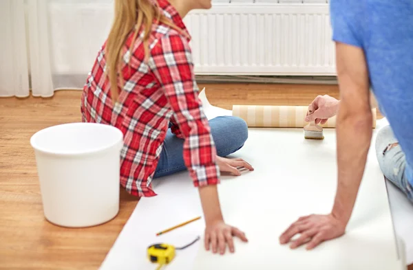 Close up of couple smearing wallpaper with glue — Stock Photo, Image