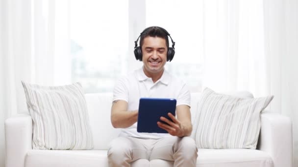 Sorrindo homem com tablet pc e fones de ouvido em casa — Vídeo de Stock