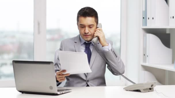 Smiling businessman with laptop calling on phone — Stock Video