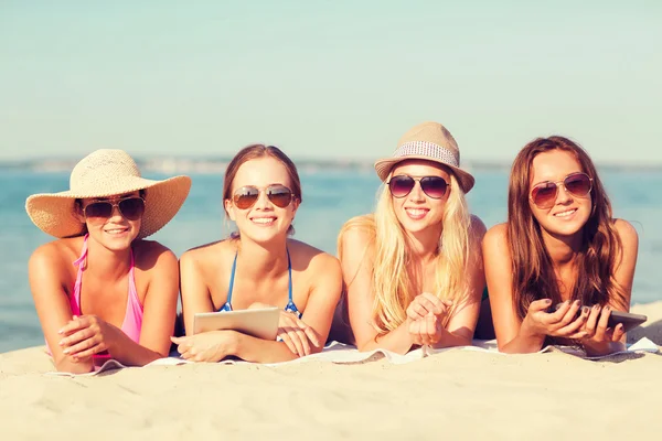 Grupo de mulheres jovens sorridentes com comprimidos na praia — Fotografia de Stock