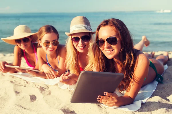 Grupo de mujeres jóvenes sonrientes con tabletas en la playa — Foto de Stock