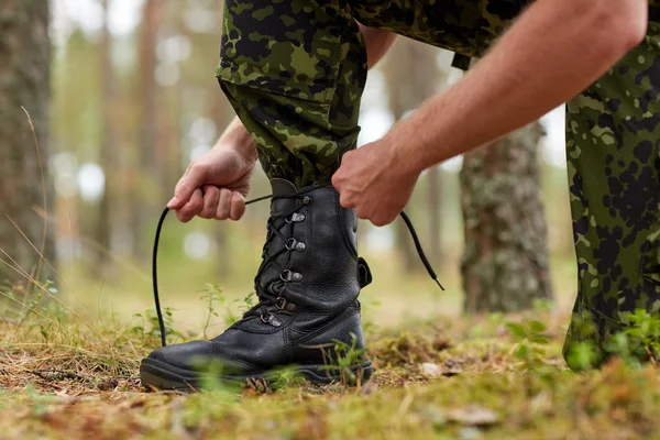 关闭的士兵在森林里绑鞋带 — 图库照片