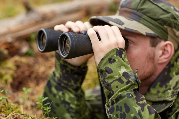 Young soldier or hunter with binocular in forest — Stock Photo, Image