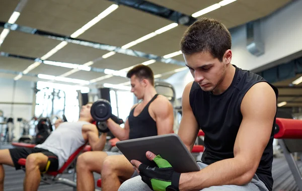 群与 tablet pc 和哑铃在健身房的男人 — 图库照片