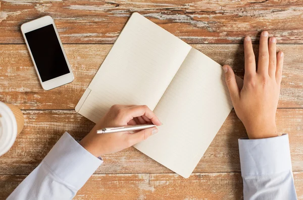 Close up of hands with notebook and smartphone — Stock Photo, Image