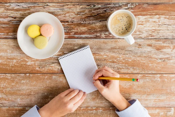 Närbild på händerna, notebook, kaffe och kakor — Stockfoto