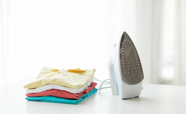 Close up of iron and clothes on table at home — Stock Photo, Image