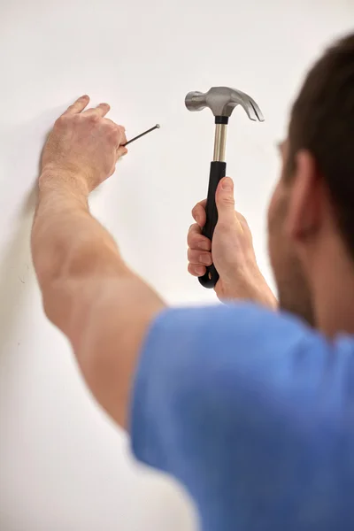 Primer plano del hombre con martillo clavo de martilleo en la pared Fotos de stock libres de derechos