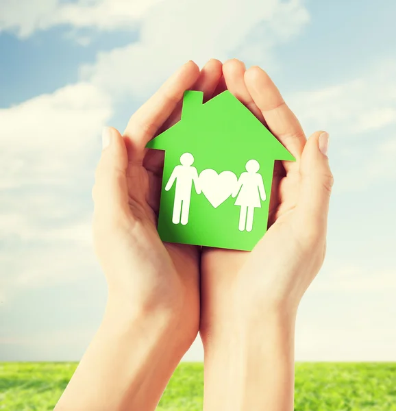 Mãos segurando casa verde com a família — Fotografia de Stock