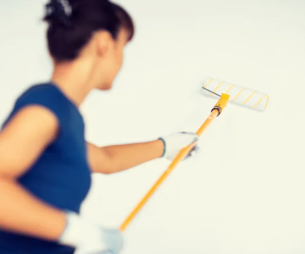 Mulher com rolo e pintura colorir a parede — Fotografia de Stock