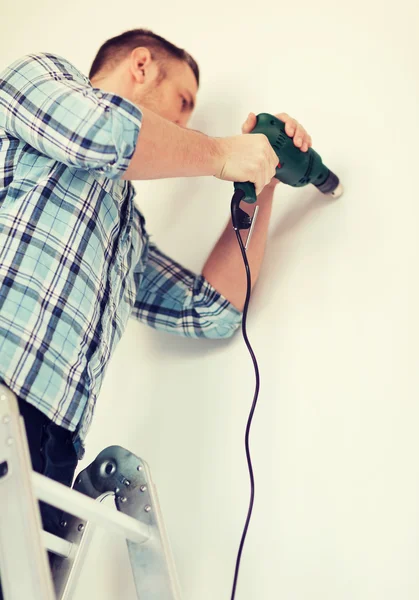 Uomo con trapano elettrico che fa foro a parete — Foto Stock