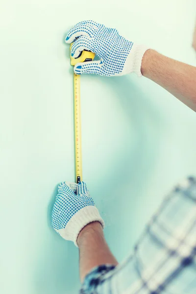Крупный план мужчины в перчатках, измеряющих стену лентой — стоковое фото