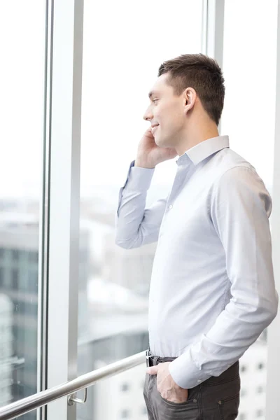 Hombre de negocios sonriente con teléfono inteligente en la oficina — Foto de Stock