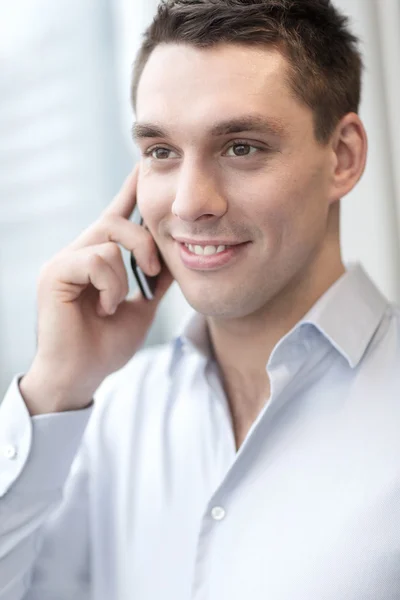 Uomo d'affari sorridente con smartphone in ufficio — Foto Stock