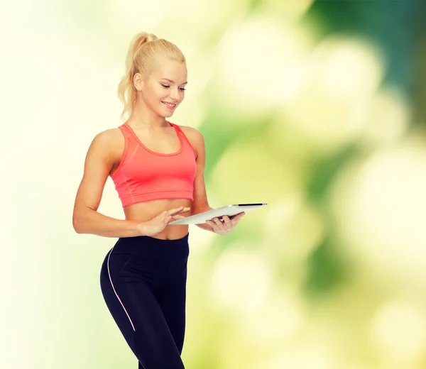 Улыбающаяся спортивная женщина с планшетным компьютером — стоковое фото