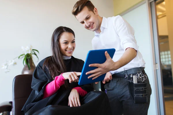 Glad kvinna och stylist med TabletPC på salong — Stockfoto