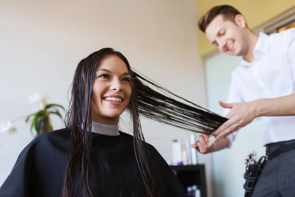 Glad kvinna med stylist skära hår på salong — Stockfoto