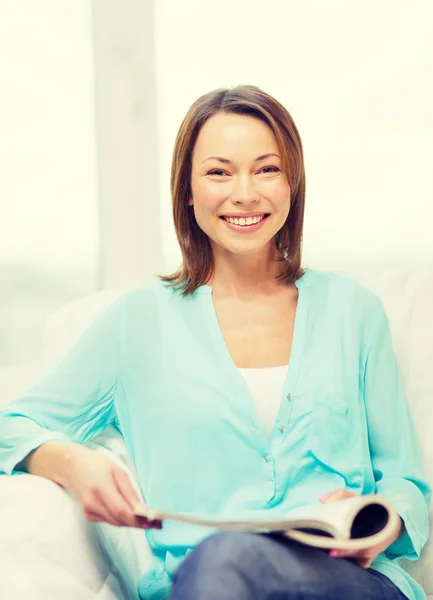 Mulher sorridente leitura revista em casa Imagem De Stock