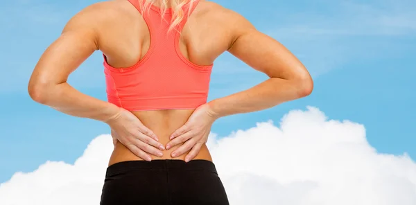 Close up de mulher esportiva tocando suas costas — Fotografia de Stock