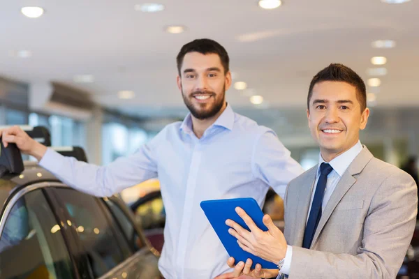 Homem feliz com negociante de carro em auto show ou salão de beleza — Fotografia de Stock