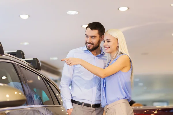 Happy couple buying car in auto show or salon — Stock Photo, Image