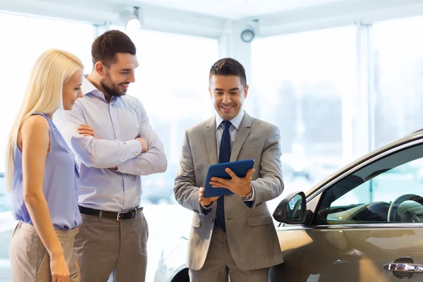 Glückliches Paar mit Autohändler in Auto-Show oder Salon — Stockfoto